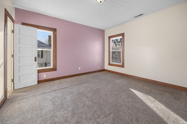 empty room with carpet floors, visible vents, and baseboards