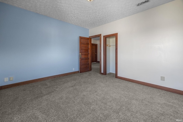 carpeted empty room with baseboards, visible vents, and a textured ceiling