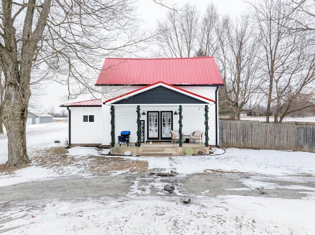 view of front of home with covered porch, fence, and metal roof