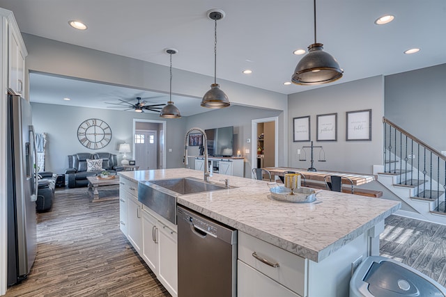 kitchen with open floor plan, stainless steel appliances, an island with sink, and white cabinetry