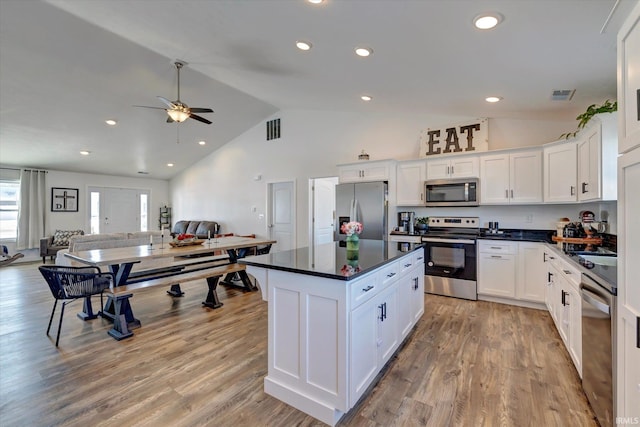 kitchen featuring dark countertops, white cabinetry, appliances with stainless steel finishes, and open floor plan