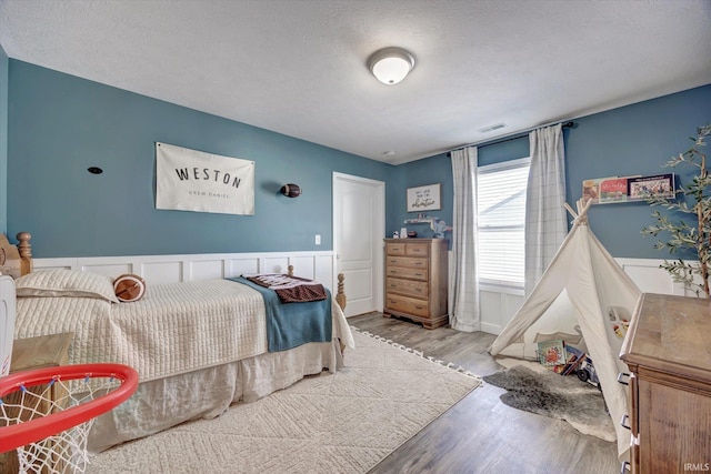 bedroom featuring a textured ceiling, wood finished floors, and visible vents