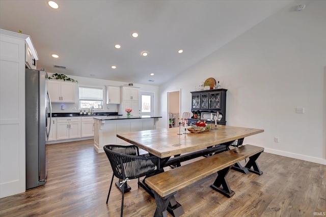 dining space featuring recessed lighting, vaulted ceiling, baseboards, and wood finished floors