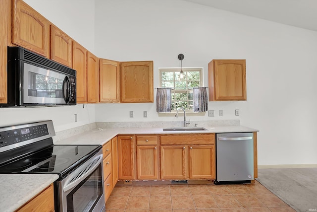 kitchen with stainless steel appliances, light countertops, a sink, and decorative light fixtures