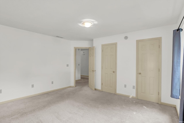 unfurnished bedroom with light colored carpet, visible vents, and baseboards