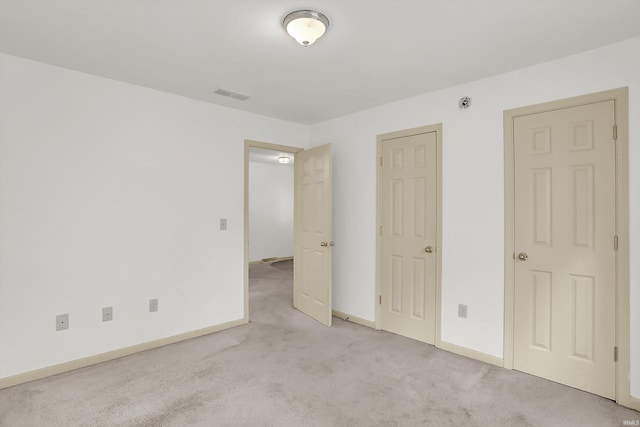 unfurnished bedroom featuring baseboards, visible vents, and light colored carpet
