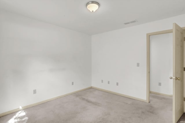 empty room with baseboards, visible vents, and light colored carpet