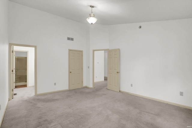 unfurnished bedroom featuring high vaulted ceiling, visible vents, light carpet, and baseboards