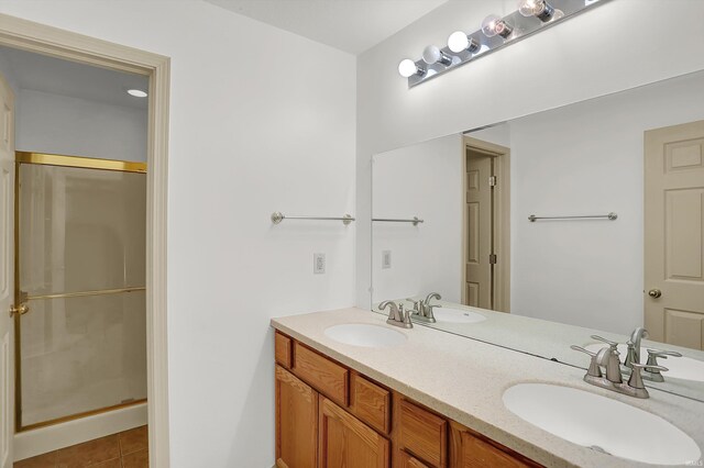 full bathroom featuring a stall shower, tile patterned flooring, a sink, and double vanity