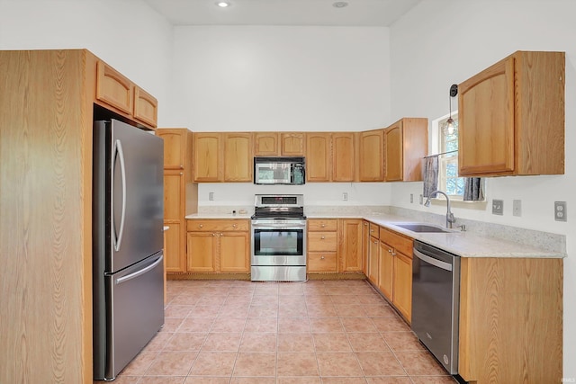 kitchen featuring a towering ceiling, appliances with stainless steel finishes, light countertops, a sink, and light tile patterned flooring