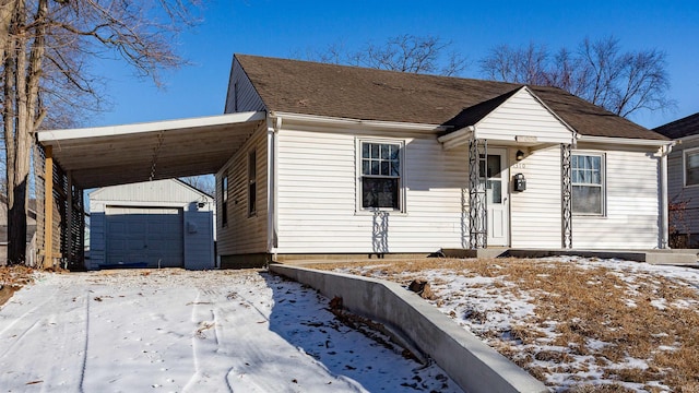 view of front facade featuring an attached carport, roof with shingles, and an outdoor structure