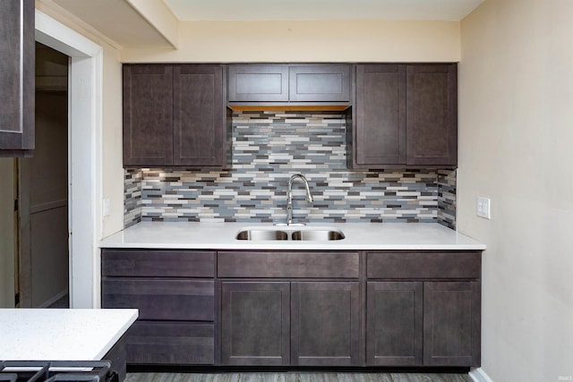 kitchen featuring tasteful backsplash, light countertops, a sink, and dark brown cabinetry