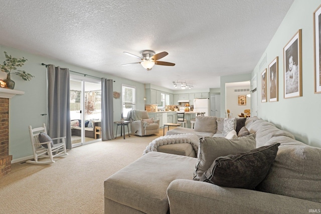 living area with a ceiling fan, light colored carpet, a fireplace, and a textured ceiling