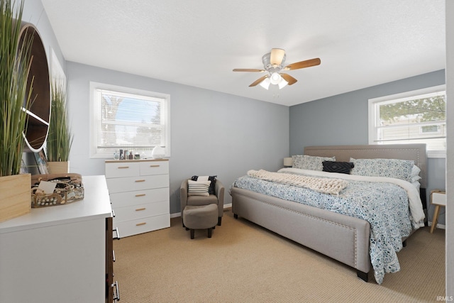 bedroom featuring light carpet, ceiling fan, multiple windows, and a textured ceiling