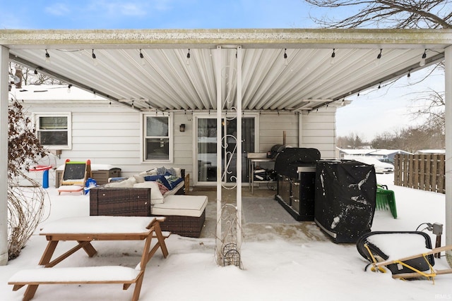 snow covered patio featuring outdoor lounge area and fence