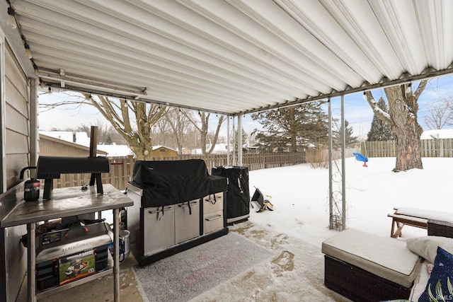 snow covered patio with a fenced backyard