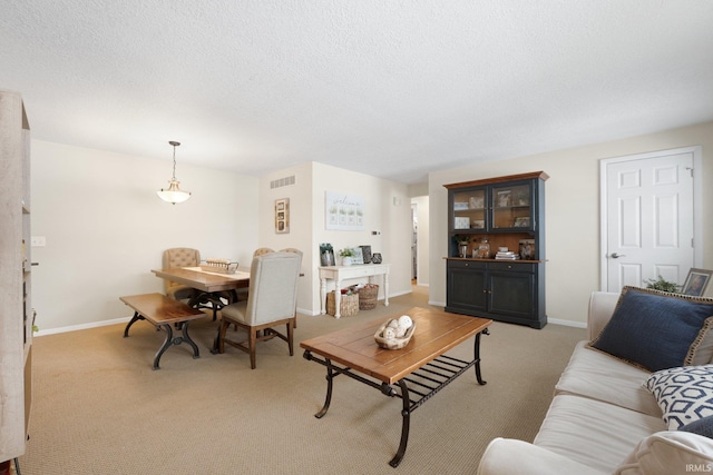 living area with light carpet, a textured ceiling, visible vents, and baseboards