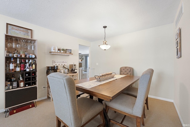 dining area featuring light carpet, visible vents, baseboards, and a textured ceiling