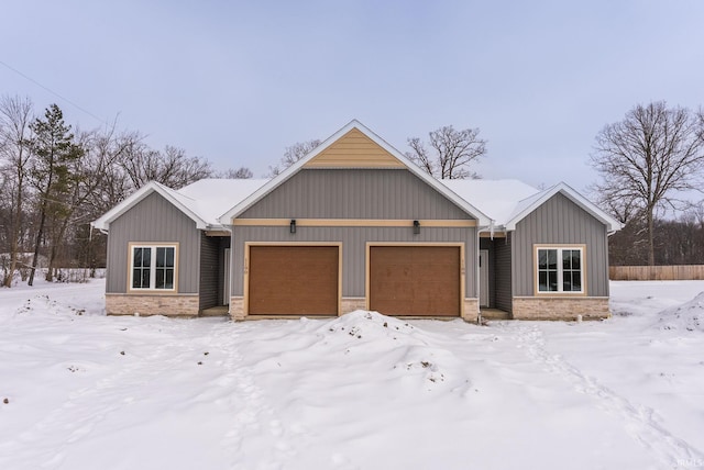 view of front facade with stone siding, board and batten siding, and an attached garage