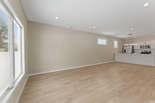 unfurnished living room featuring light wood-style floors, baseboards, and recessed lighting