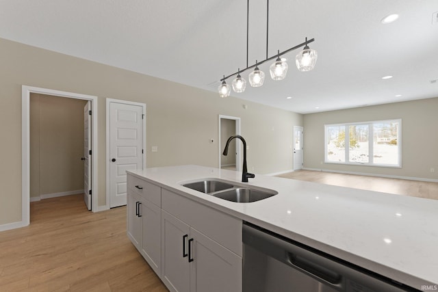 kitchen with pendant lighting, stainless steel dishwasher, light wood-style floors, a sink, and light stone countertops