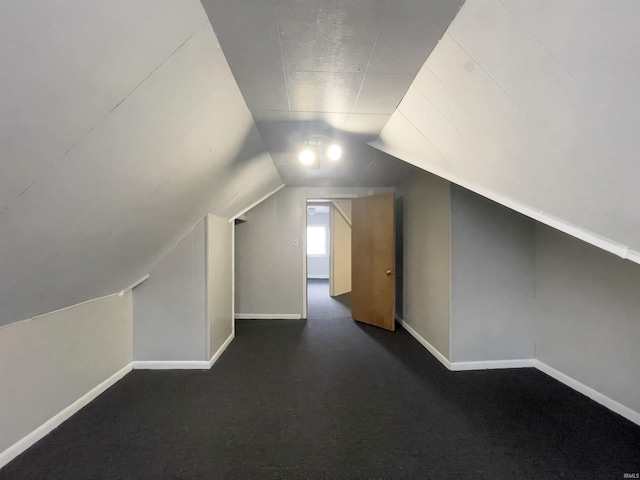 bonus room with lofted ceiling, baseboards, and dark colored carpet