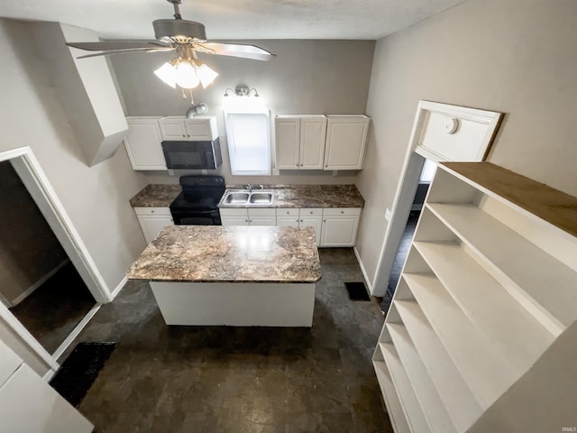 kitchen featuring black range with electric cooktop, a kitchen island, baseboards, and white cabinetry