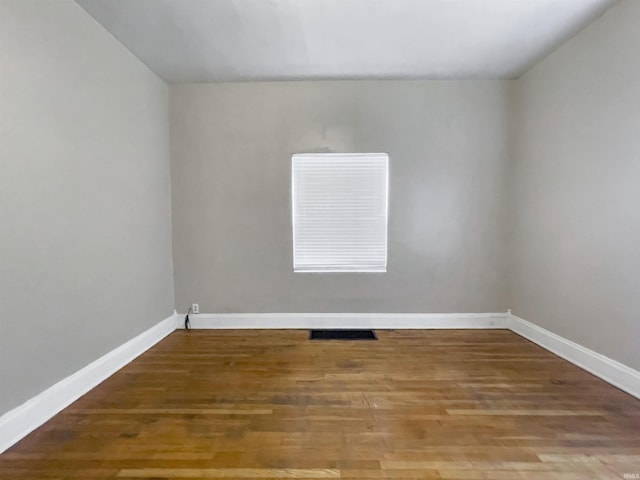 spare room with baseboards, visible vents, and wood finished floors