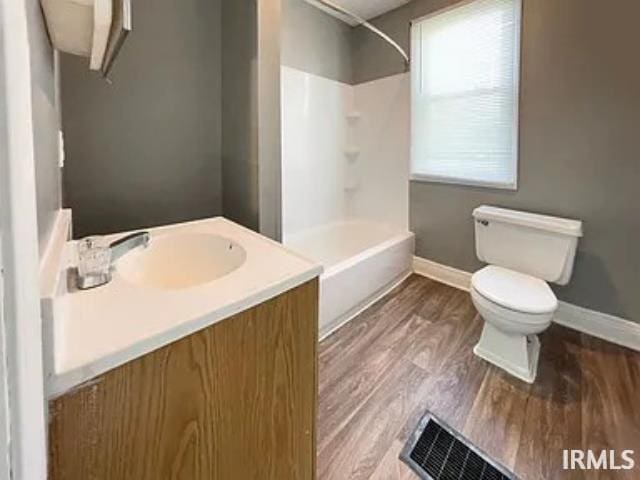 bathroom featuring a shower, visible vents, toilet, vanity, and wood finished floors