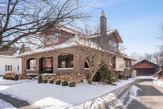 view of front of property with covered porch, brick siding, a detached garage, and an outdoor structure