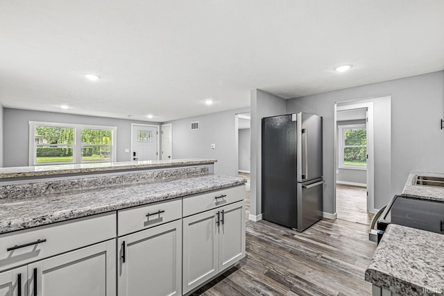 kitchen with dark wood-type flooring, freestanding refrigerator, white cabinets, range with electric cooktop, and baseboards