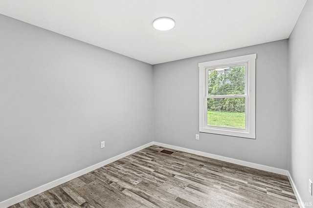 unfurnished room with wood finished floors, visible vents, and baseboards