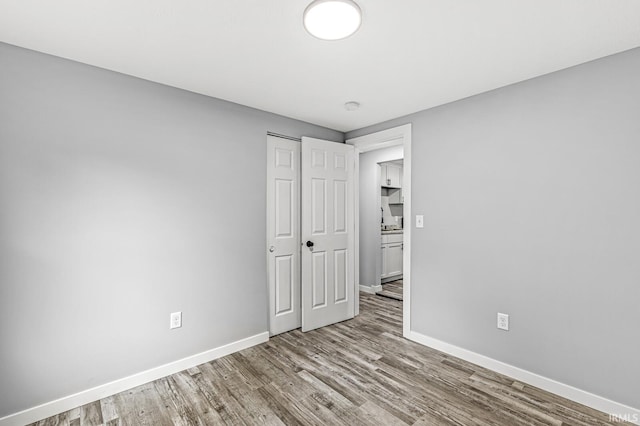 unfurnished bedroom with a closet, light wood-style flooring, and baseboards