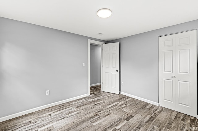 unfurnished bedroom featuring a closet, baseboards, and wood finished floors