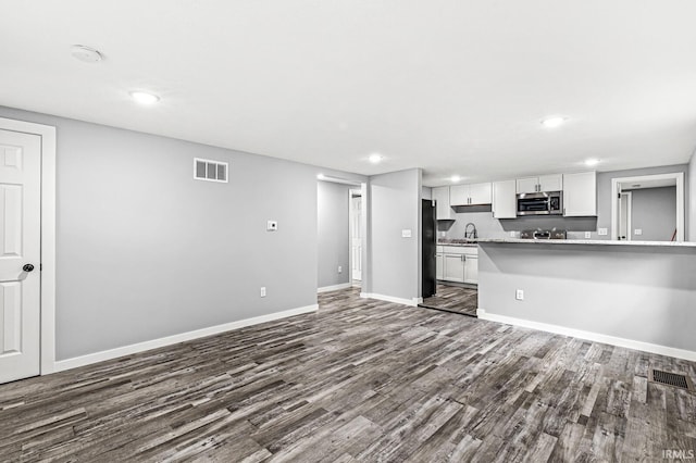 kitchen with light countertops, stainless steel microwave, visible vents, freestanding refrigerator, and white cabinetry