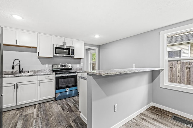 kitchen featuring dark wood-style floors, stainless steel appliances, visible vents, and white cabinetry