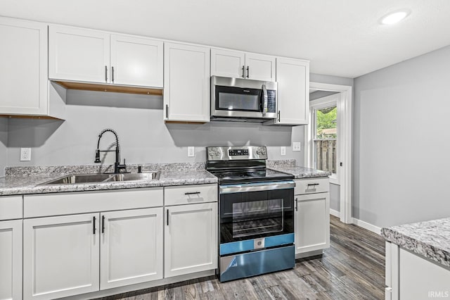 kitchen featuring dark wood-type flooring, white cabinetry, stainless steel appliances, and a sink