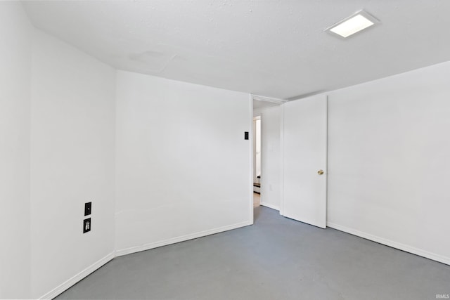 unfurnished room with finished concrete flooring, a baseboard heating unit, and baseboards