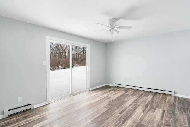 spare room with a baseboard radiator, wood finished floors, a ceiling fan, and baseboards