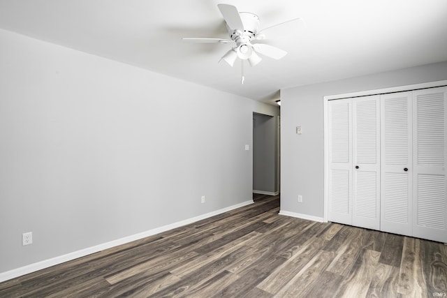 unfurnished bedroom featuring dark wood-type flooring, a closet, baseboards, and a ceiling fan