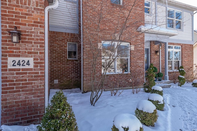 snow covered property with brick siding