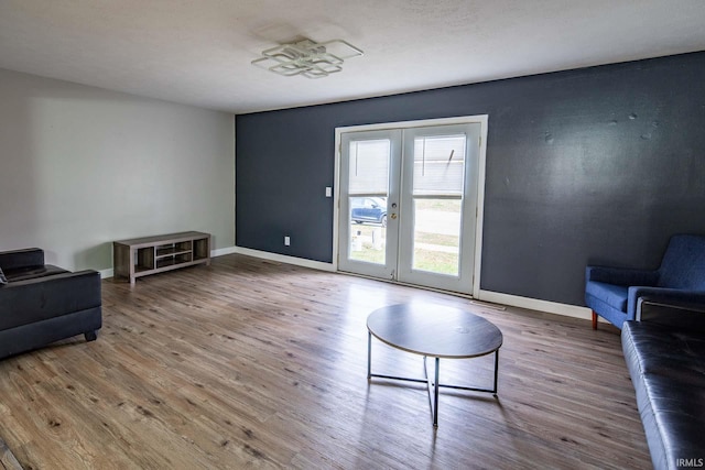 living area with french doors, baseboards, and wood finished floors