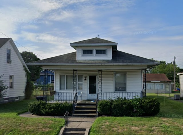 bungalow-style house featuring covered porch, a front lawn, and central air condition unit