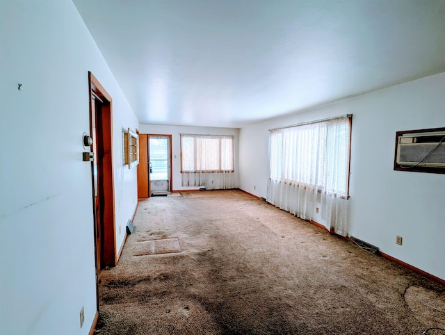 spare room with carpet floors, baseboards, and a wall mounted AC