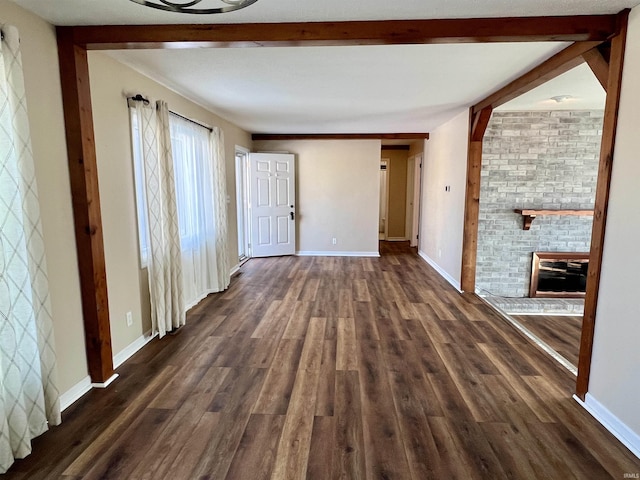 interior space featuring dark wood-type flooring, beamed ceiling, and baseboards