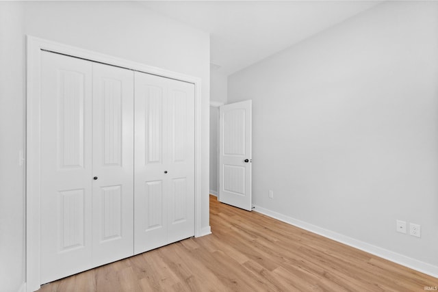 unfurnished bedroom with light wood-type flooring, a closet, and baseboards