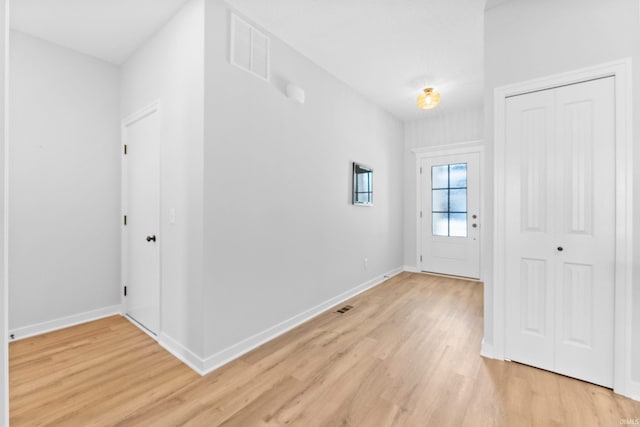 foyer entrance featuring visible vents, light wood-style flooring, and baseboards