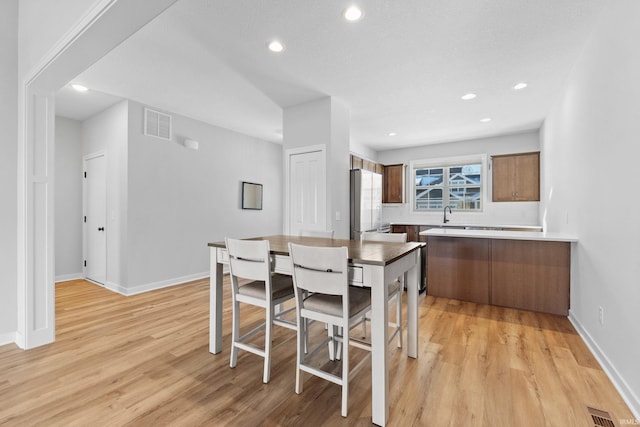 kitchen featuring brown cabinetry, freestanding refrigerator, light countertops, and light wood finished floors