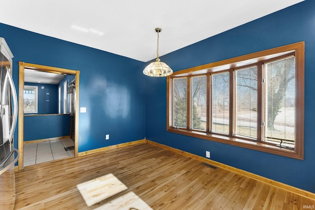 unfurnished room featuring light wood-style flooring, a chandelier, and baseboards