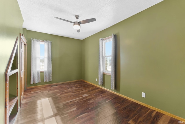 spare room featuring dark wood-style floors, baseboards, and a ceiling fan